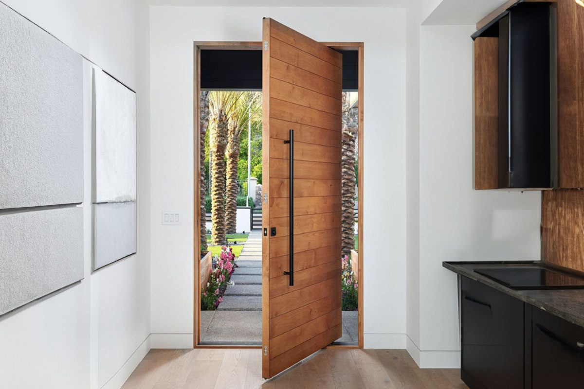 High-end pivot doors with vertical grain wood finish in a stylish foyer.