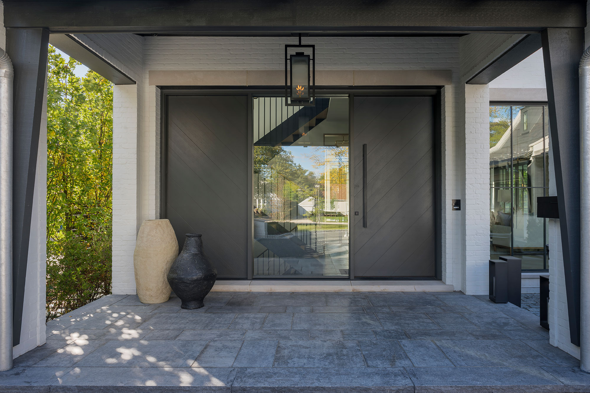 Modern black front door with sleek handle and glass panel.