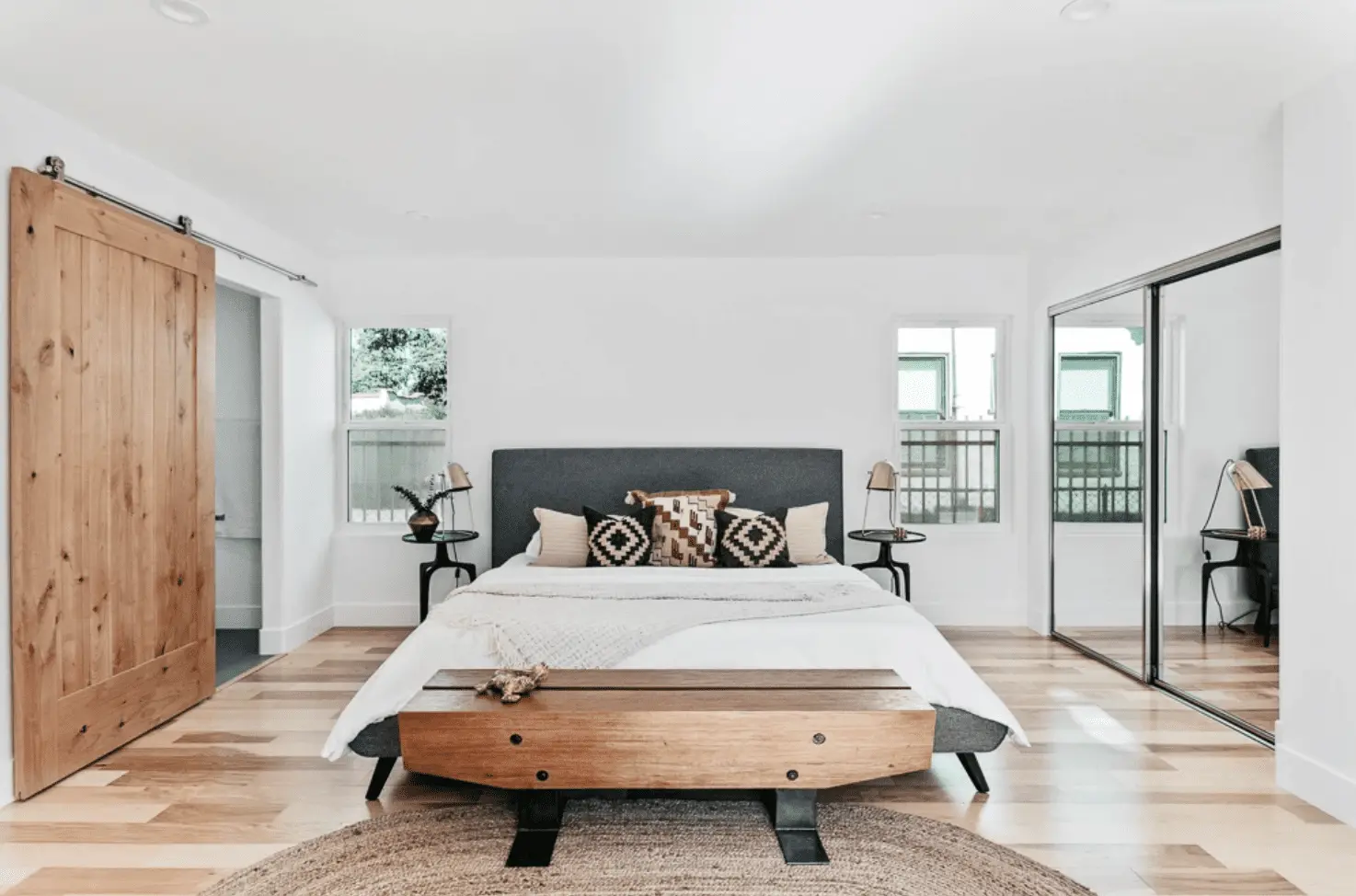 Rustic sliding wood barn door with black metal hardware in a modern farmhouse living room.